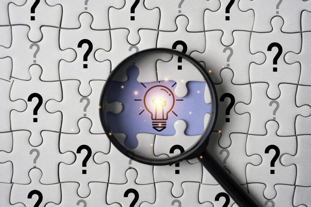 glowing light bulb inside magnifier glass among question mark on jigsaw puzzle for focus and concentrate of creative thinking idea and problem solving concept. glowing light bulb inside magnifier glass among question mark on jigsaw puzzle for focus and concentrate of creative thinking idea and problem solving concept.